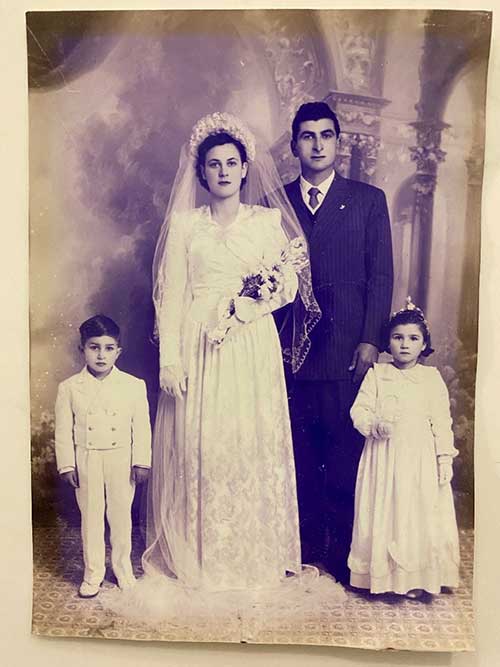 Portrait d’archives des deux mariés le jour de leur mariage, deux petits enfants habillés en blanc à leurs côtés.