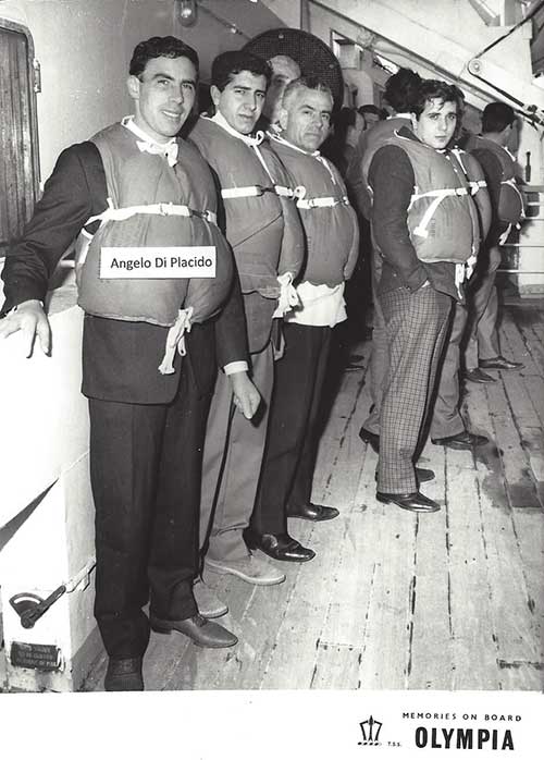 Quatre hommes portant des gilets de sauvetage et debout sur le pont du navire.