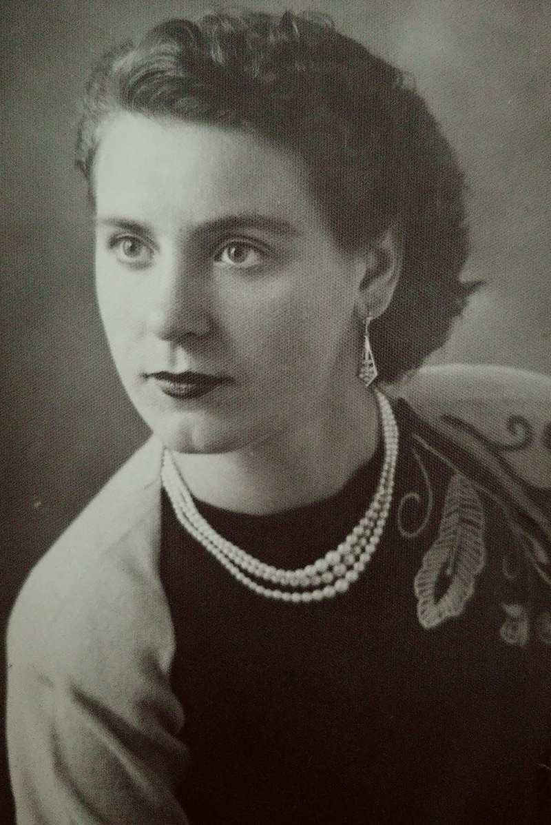 Portrait professionnel d’une jeune femme aux cheveux noirs et portant un collier de perles.