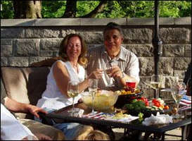 Couple d’âge moyen assis à une table à l’extérieur, portant un toast. 