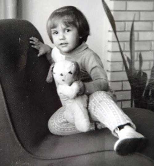 Une jeune fille assise sur une chaise tient un ours en peluche.