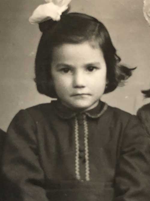 Une jeune fille portant une grosse boucle sur la tête regarde en direction de l’appareil photo sans sourire.