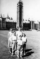 Homme, femme et enfants debout devant un grand immeuble du gouvernement.