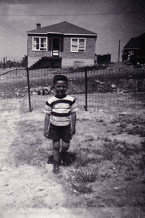 Un petit garçon portant un short et un t-shirt se tenant à l’extérieur de la clôture pour la photo.