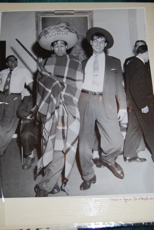 Photo en noir et blanc de deux hommes italiens, l’un portant un costume et l’autre un chapeau portant l’inscription Florida et tenant un fusil.