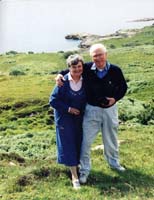 Catherine et Gordon en couple, plus âgés, sur une colline herbeuse.