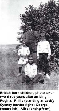 Homme et trois enfants, debout dans un champ devant un arbre. 