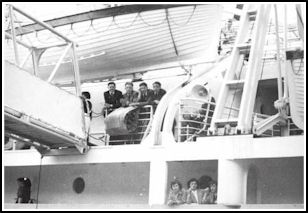 De jeunes hommes penchés sur la rambarde sur le pont du navire.