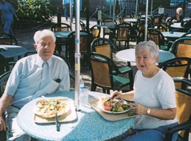 Un couple plus âgé assis à la table du restaurant, avec des assiettes de nourriture devant eux.