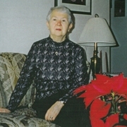 Femme plus âgée assise sur le canapé avec poinsettia au premier plan.