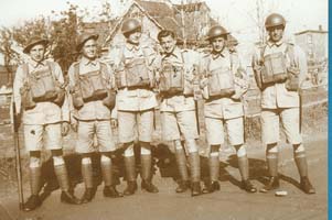 Vieille photographie montrant six jeunes hommes debout en uniformes de l’armée. 