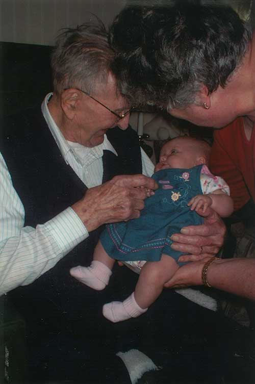 Un homme âgé regarde affectueusement l’adorable petit bébé qui se trouve sur ses genoux.