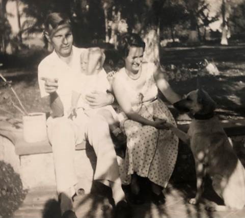 Photo en tons sépia d’un homme et d’une femme néerlandais blancs assis à l’extérieur avec un bébé et un gros chien.