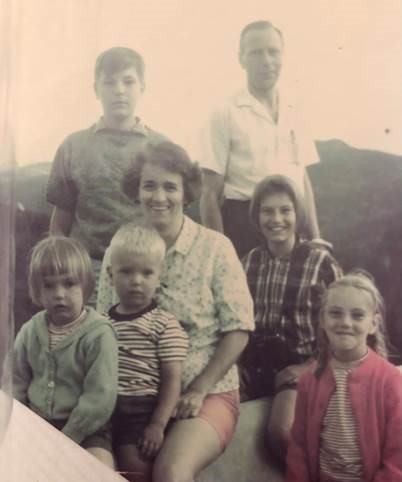 Vieille photo d’une famille blanche posant à l’extérieur, comprenant un homme, une femme et cinq enfants d’âges différents.