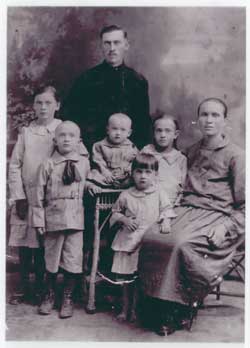Vieux portrait de famille de la mère assise et de cinq enfants et du père debout sur sa droite.