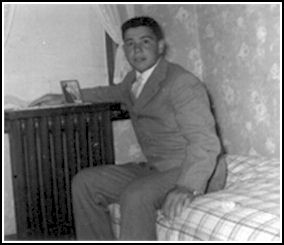 Jeune homme assis sur le lit par la fenêtre de la chambre.