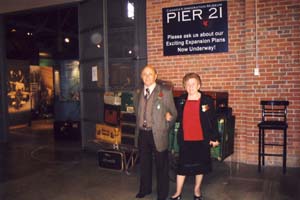 Homme et femme debout sous le panneau du quai 21, devant l’étalage des bagages.