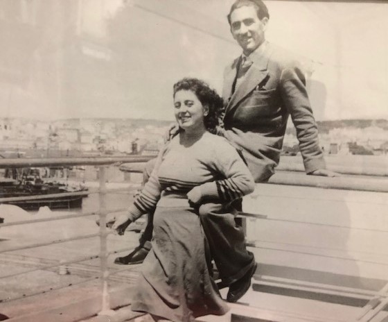 Un jeune homme s’assied sur la rambarde d’un navire et une jeune femme se tient devant lui.