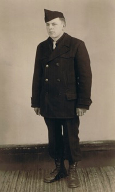 Un jeune homme porte un uniforme et se tient devant un mur.