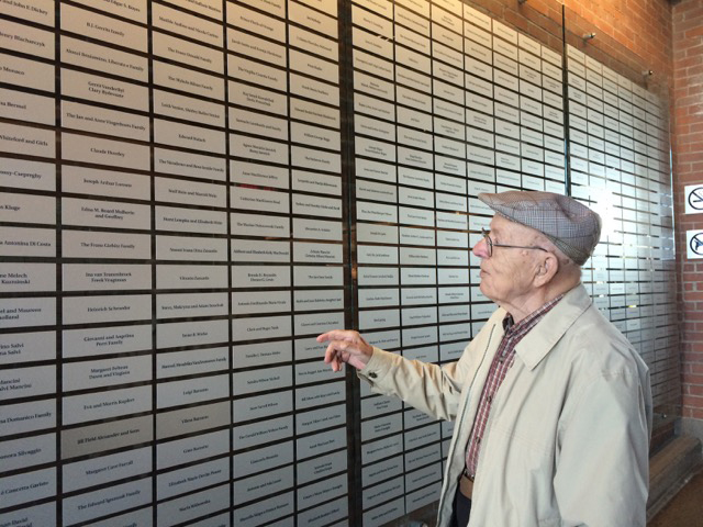 Un homme se tient devant le mur d’honneur de Sobey au Musée canadien de l’immigration du Quai 21.