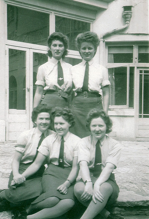 Cinq jeunes femmes posent pour une photo.