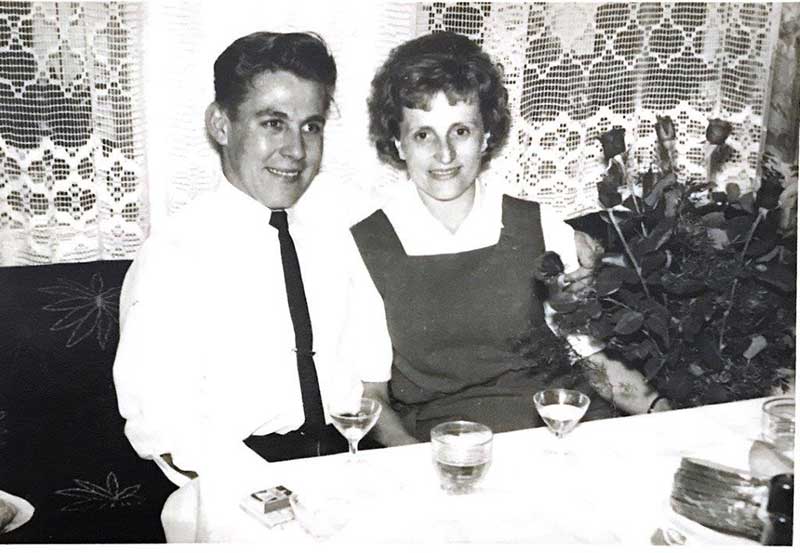 Un jeune homme et une jeune femme sont assis côte à côte et boivent du vin