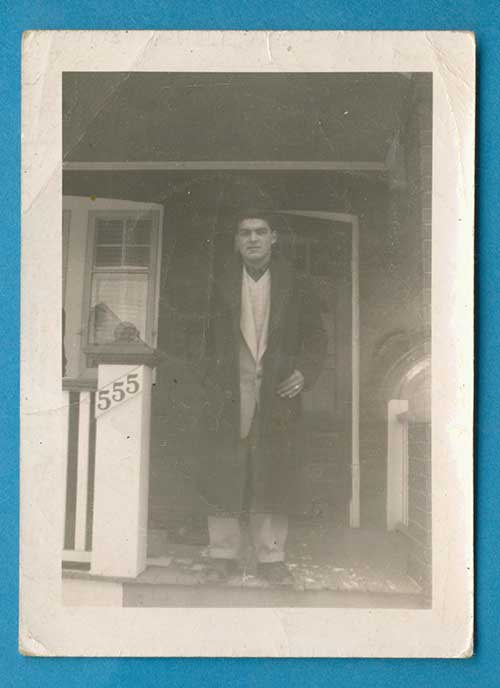 Le jeune homme debout dans un porche a la maison numéro 555 sur son côté droit.