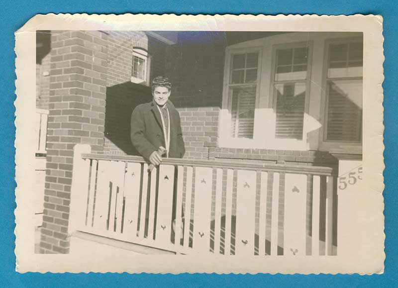 Un jeune homme se tient dans un porche et la lumière brille sur lui.