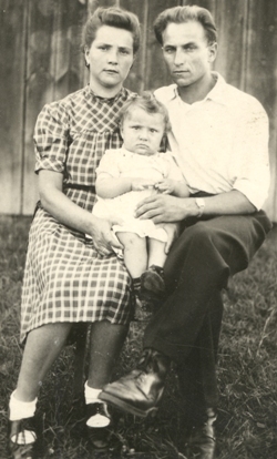 Homme et femme assis devant une clôture, un bébé sur leurs genoux.