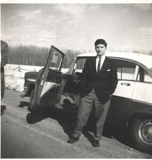 Jeune homme debout devant la porte ouverte de la voiture sur le côté de la route.