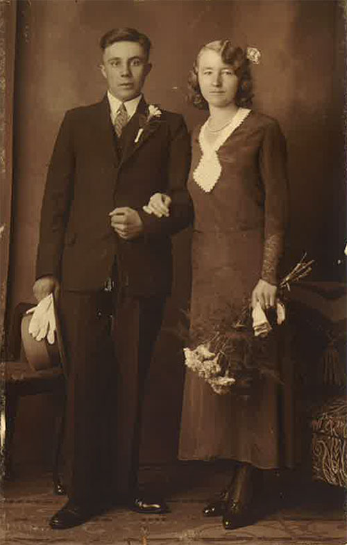 Une femme bien habillée est à côté d’un jeune homme et tient des fleurs dans sa main gauche.