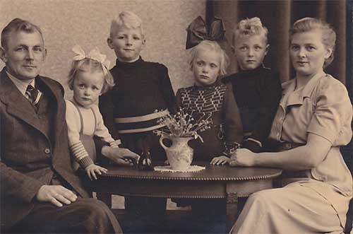 Homme et femme avec quatre enfants assis autour de la table.