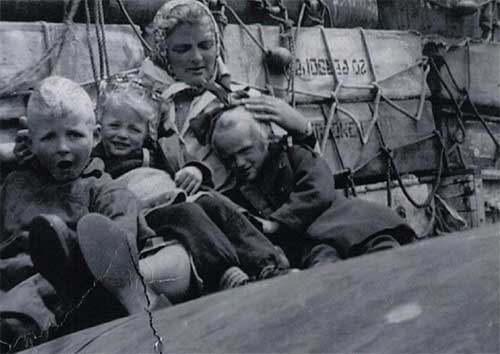 Une jeune femme avec trois enfants assis sur un bateau.