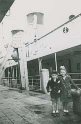Deux petits enfants sur le quai avec le navire assis à côté.