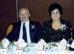 Photo en couleur d’un homme et d’une femme âgés assis à une table de banquet.