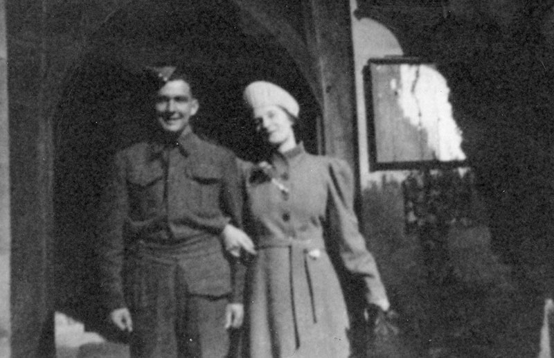 Un jeune homme en uniforme militaire, avec une femme à côté de lui tenant son bras.