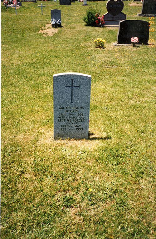 Une pierre tombale se trouve dans un cimetière d’herbe verte.
