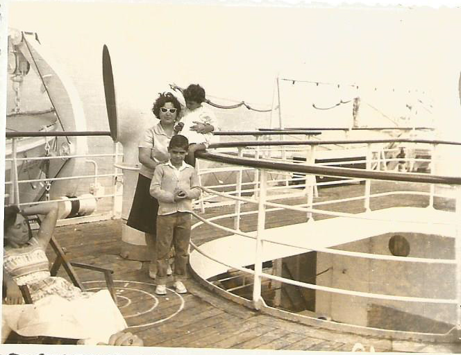 Une femme et deux enfants se tiennent près des balustrades du navire.