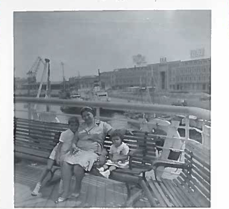 Une femme est assise sur le pont arrière avec deux enfants.