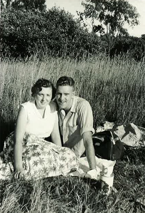Un jeune homme et une jeune femme font un pique-nique dans la grande herbe.