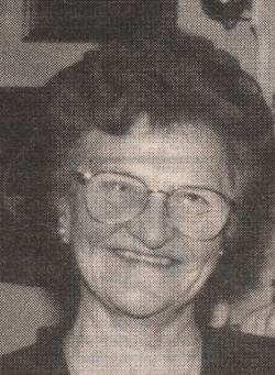 Photographie en portrait d’une femme plus âgée aux cheveux courts brun et portant des lunettes.