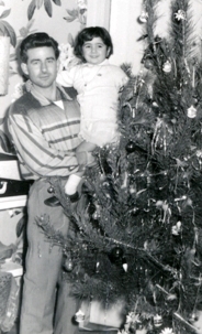 Photo plus ancienne d’un homme avec un petit enfant, debout à côté d’un arbre de Noël.