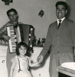 Homme tenant la main d’une petite fille avec un joueur d’accordéon derrière eux.
