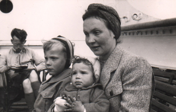 Mère avec deux enfants sur les genoux, assise sur le pont du navire.
