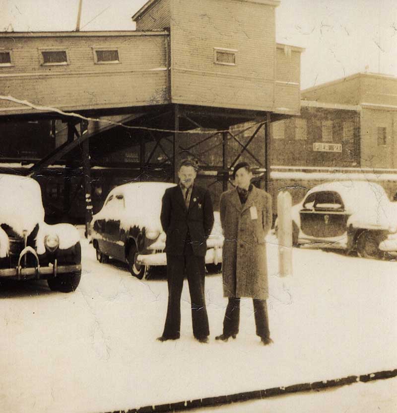 Deux jeunes hommes sont debout dans la neige devant le quai 21.