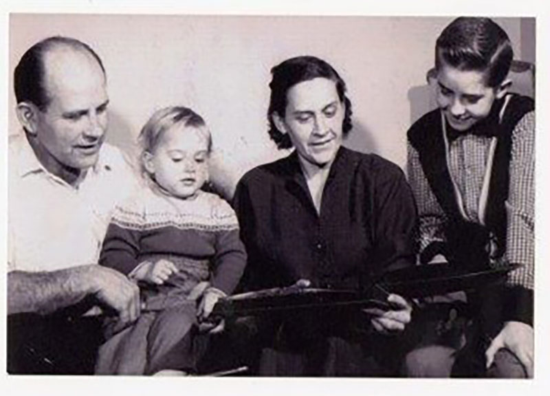 Un homme et une femme regardent un livre ouvert avec leurs enfants.