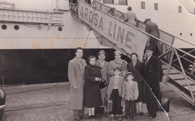 La famille se tient devant un navire, à côté de la passerelle.
