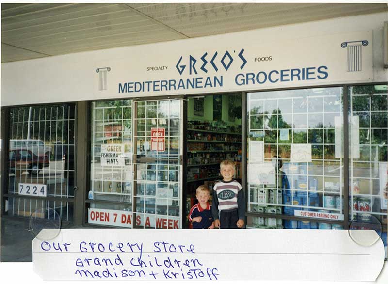 Deux jeunes garçons devant une épicerie grecque.