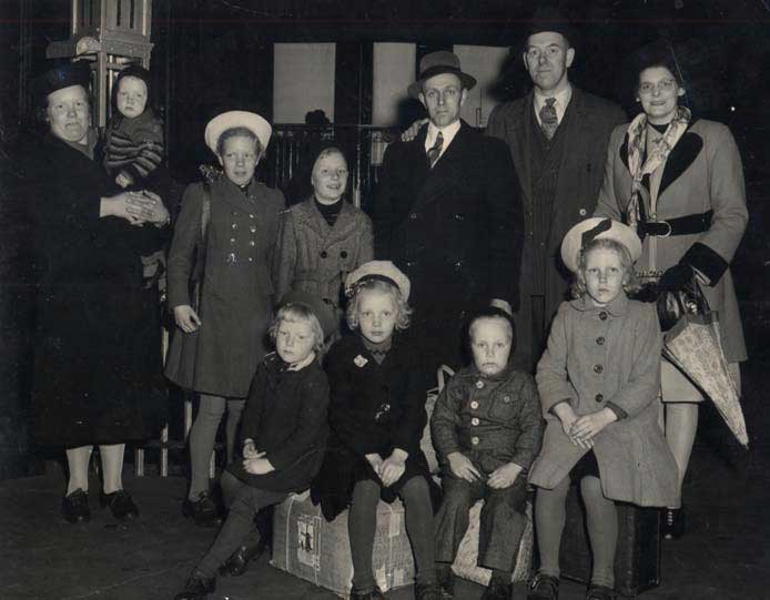 Groupe de personnes bien habillées avec bagages assis et debout pour la photo.