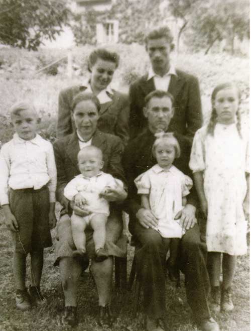 Une photo de famille archivée avec quatre adultes et quatre enfants.